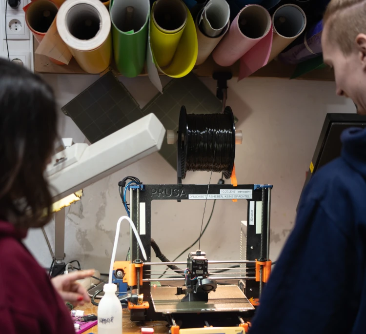Two people standing in front of a 3D printer