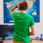 Bild von eest9 wenn wesen in wesens Zimmer vor einer Weltkarte steht während wesen sich auf den Kopf greift.